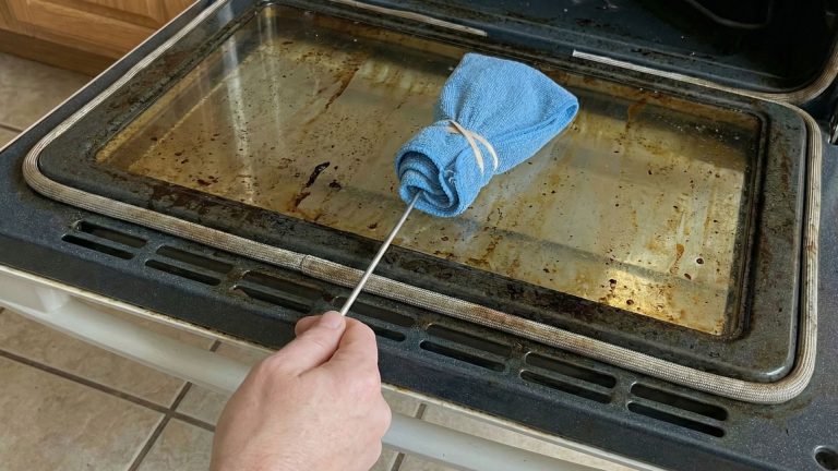 Nettoyage de l'espace entre les deux vitres de la porte du four avec un cintre métallique et un chiffon microfibre.